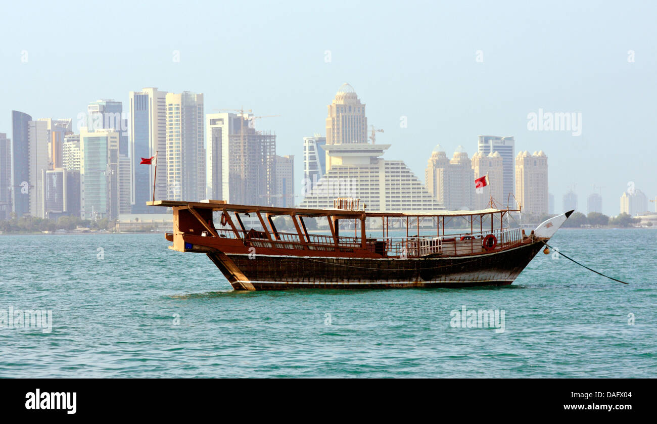 Eine Dhau als Passagierfähre über die Bucht von Doha, New West Bay Commercial Center im Hintergrund, Doha, Katar Stockfoto