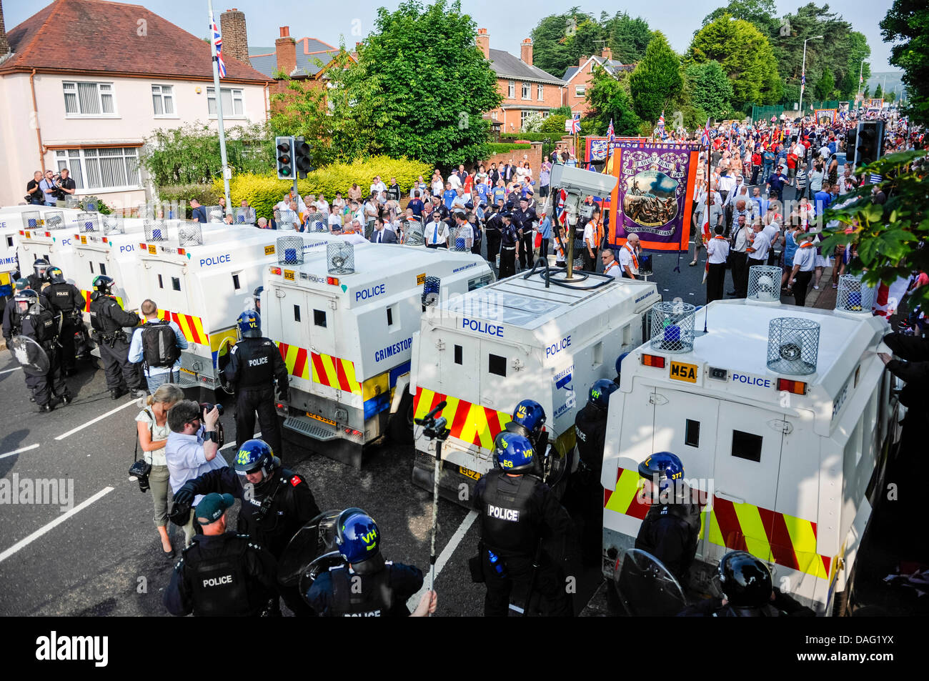 Belfast, Nordirland, 12. Juli 2013 - Hunderte von Mitgliedern der Oranier-Orden, Kapellenmitglieder und unterstützt verhindert Verfahren durch PSNI gepanzerte Landrover und Offiziere in Kampfmontur. Stockfoto