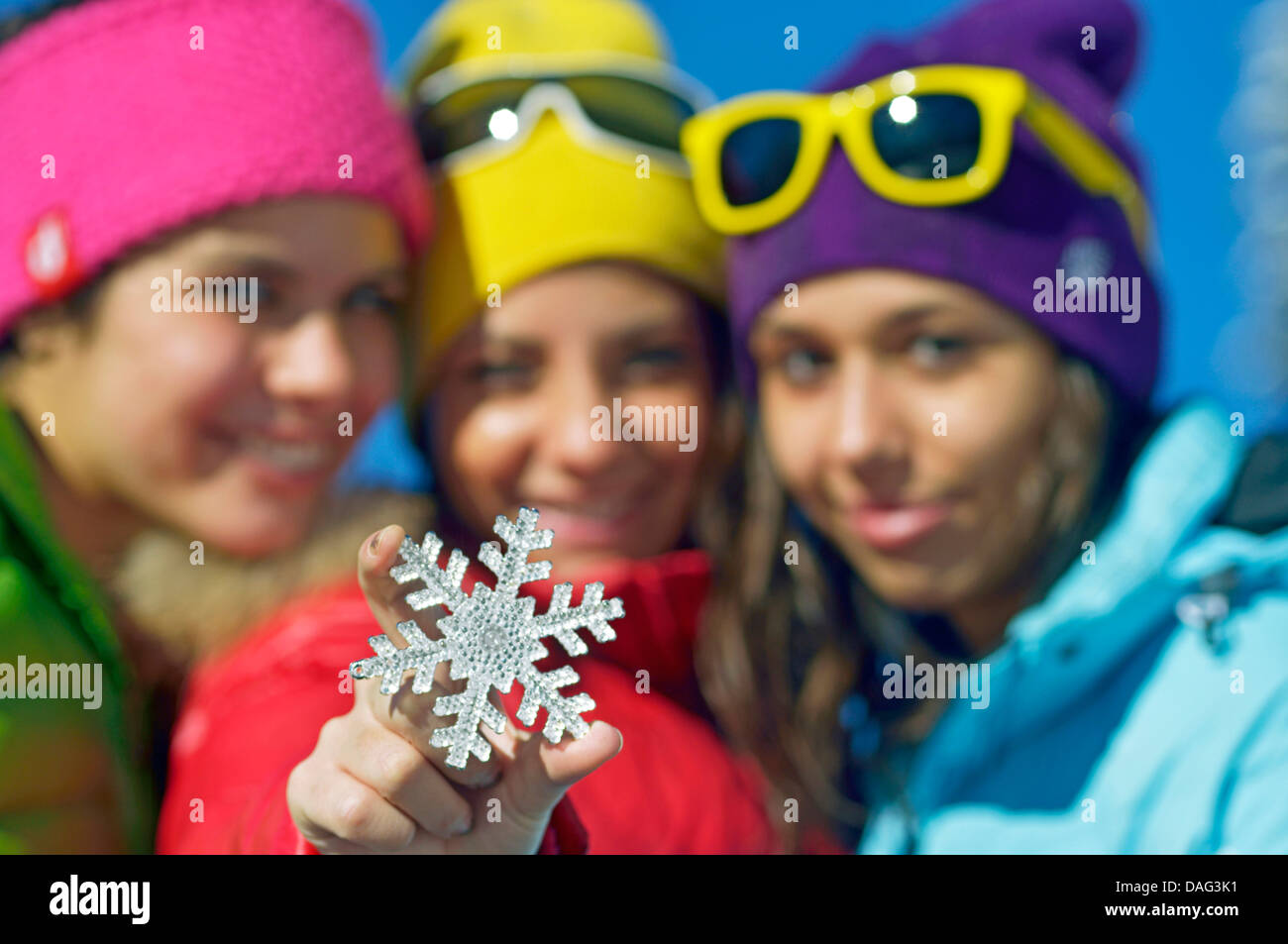 drei Mädchen im Teenageralter auf Winterurlaub gerne präsentieren ein Schneeflockensymbol, Frankreich Stockfoto