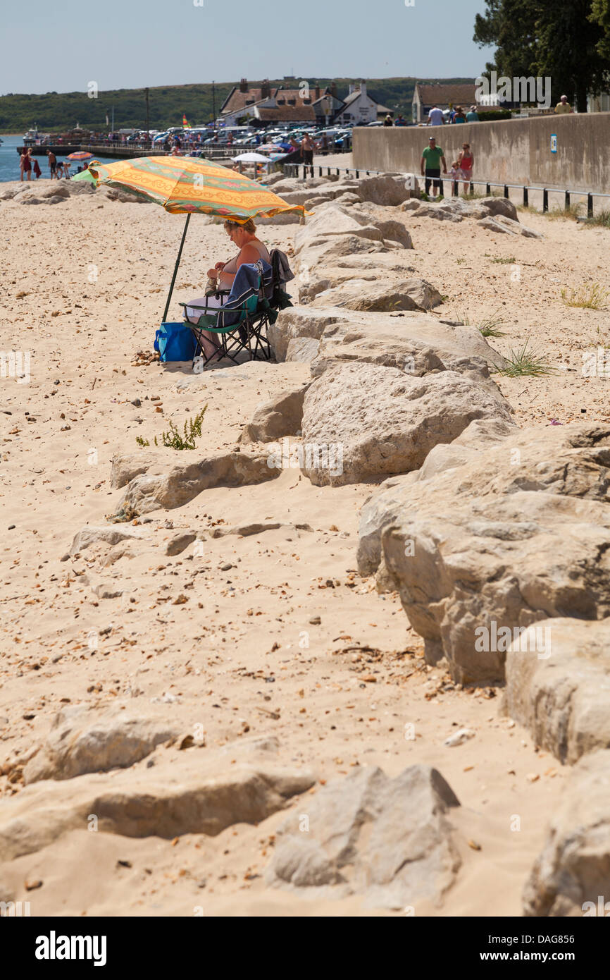 einem mittleren Alters Frau unter Sonnenschirm von Felsen Stockfoto