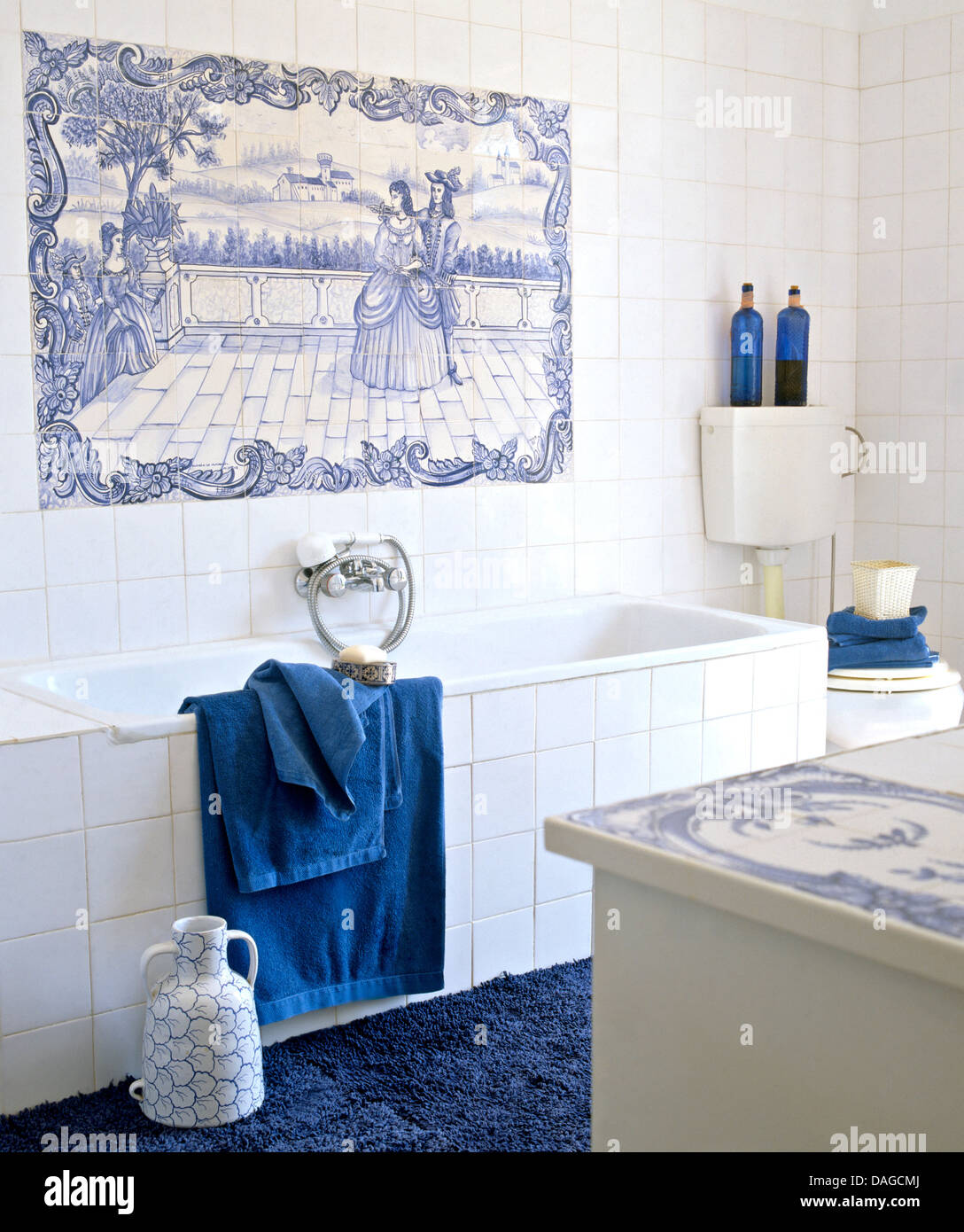 Blau + weiß gefliest Dekorplatte über Bad mit weißen Fliesen Surround in  weiß geflieste Badezimmer mit blauen Tüchern und Teppich Stockfotografie -  Alamy