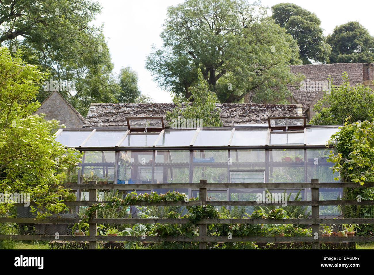 Glashaus In Einem Garten Umgeben Von Einem Holzzaun Stockfoto