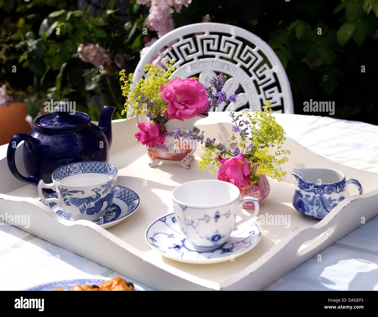 Nahaufnahme der blaue + weiße Tassen und Krug mit Teekanne auf weiß lackiertem Tablett mit Blumensträuße Sommer Blumen in Vasen Stockfoto