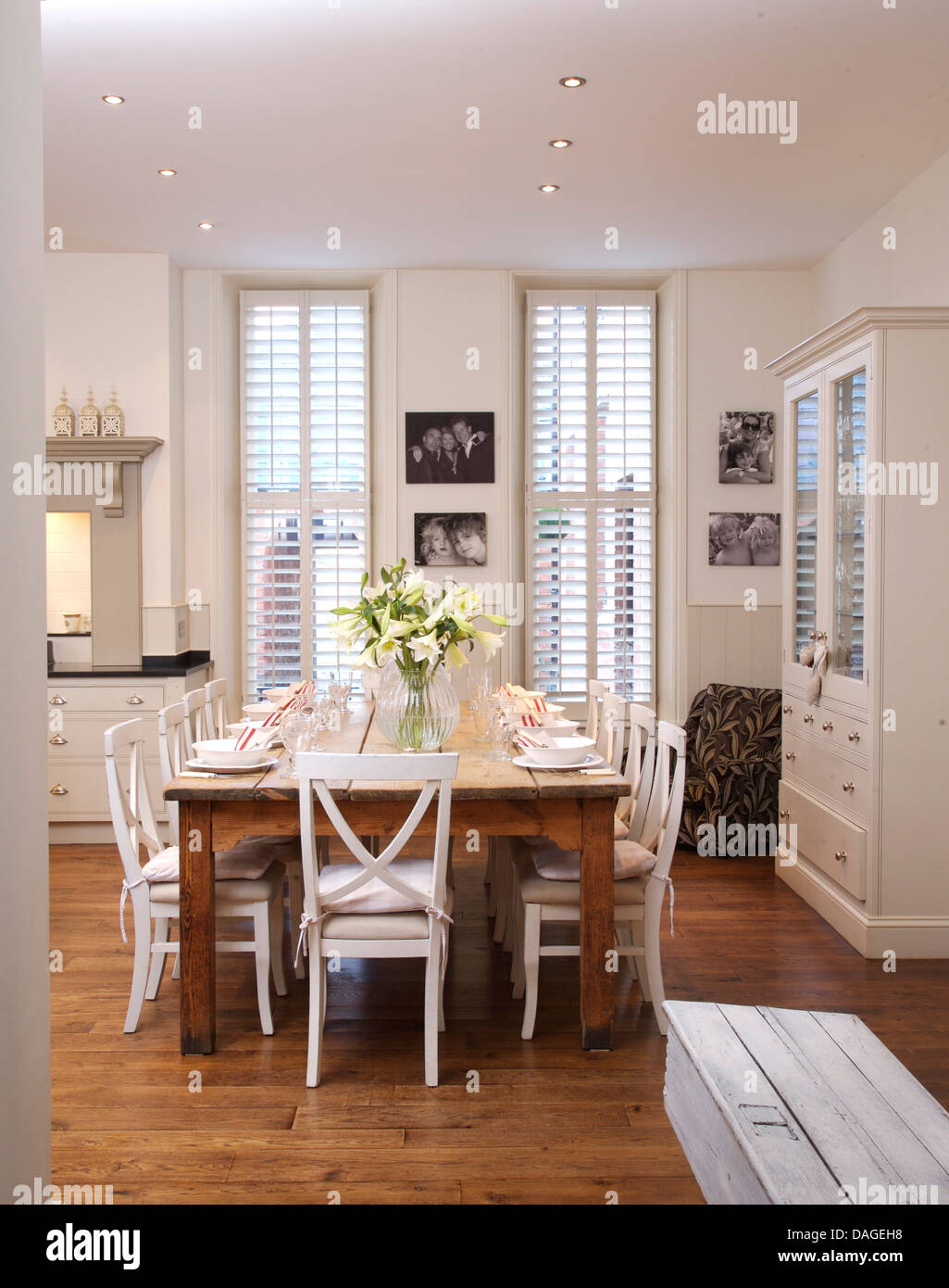 Weiße Stühle bei einfachen Holztisch in modernen weißen Küche Esszimmer mit  Parkettboden und weiße Plantage Fensterläden Stockfotografie - Alamy