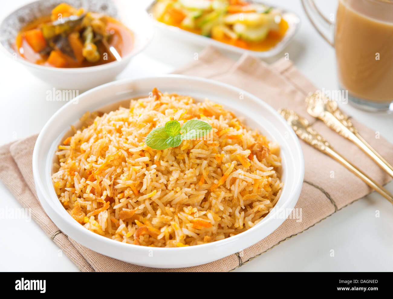 Indische vegetarische Kost. Biryani Reis, Dhal curry und Milch Tee am Esstisch. Stockfoto