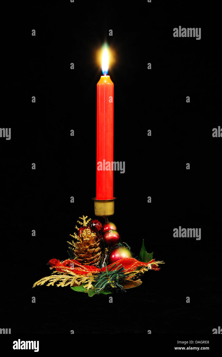 Rote Kerze in einem Weihnachts-Halter vor einem schwarzen Hintergrund. Stockfoto