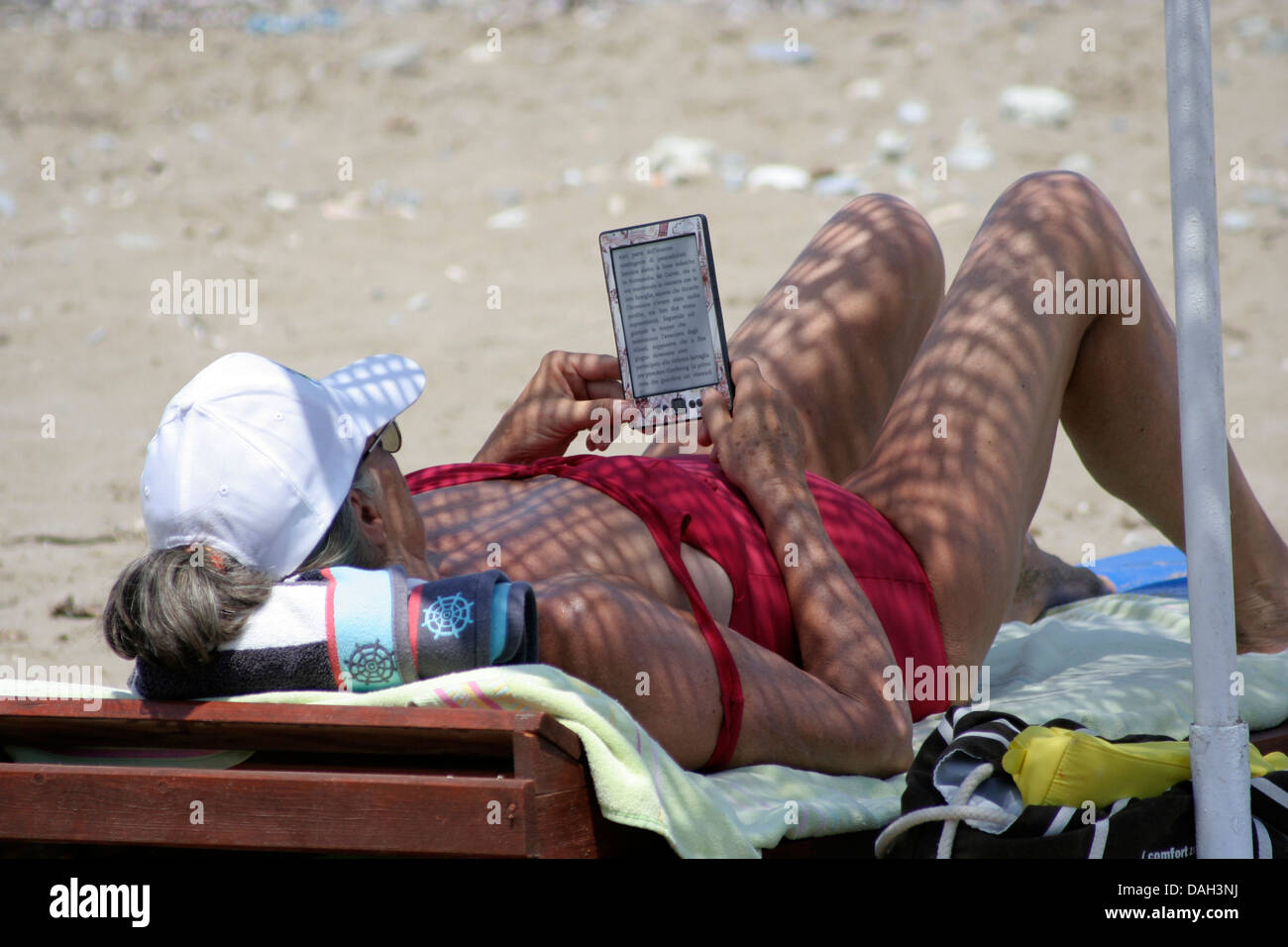 Eine Frau mit einem E-Book am Strand Stockfoto