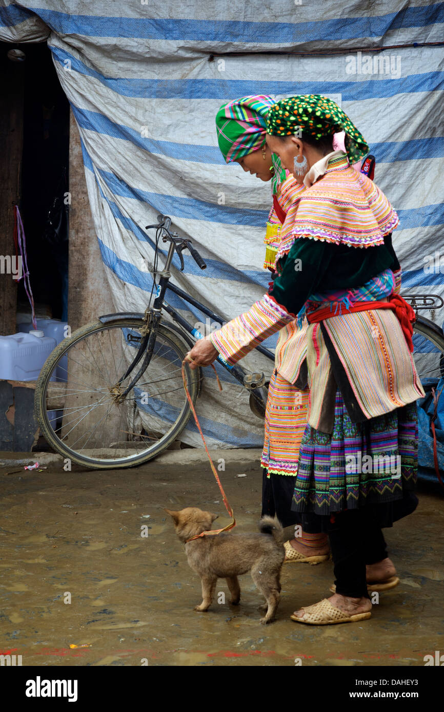 Flower Hmong Frauen mit einem Welpen am Markt von Bac Ha, Vietnam. Ältere Hunde landen immer auf den Teller in Vietnam. Stockfoto