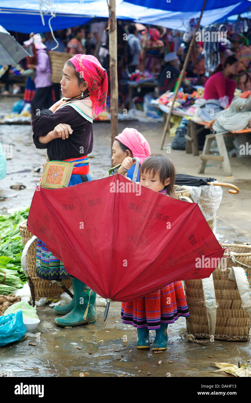 Junge Hmong Mädchen spielen mit einem Regenschirm auf Markt, Bac Ha, Vietnam Stockfoto