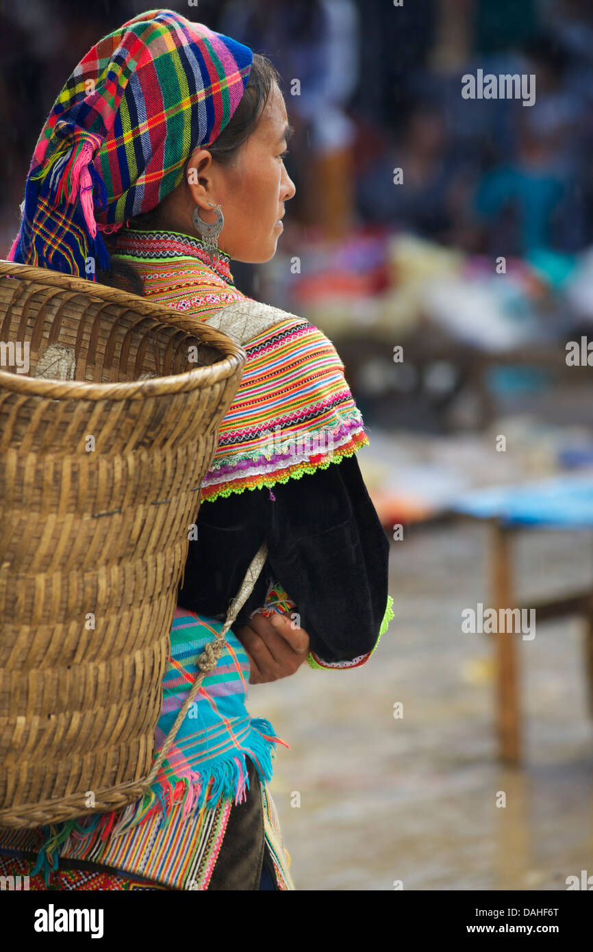 Flower Hmong Frau in unverwechselbaren Stammes-Kleid mit Carry Korb auf Rückseite. Markt von Bac Ha, Provinz Lao Cai, Vietnam Stockfoto