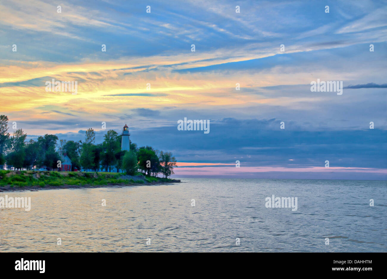 Leuchtturm am Horizont mit Sonnenuntergang Himmel im Hintergrund. Stockfoto