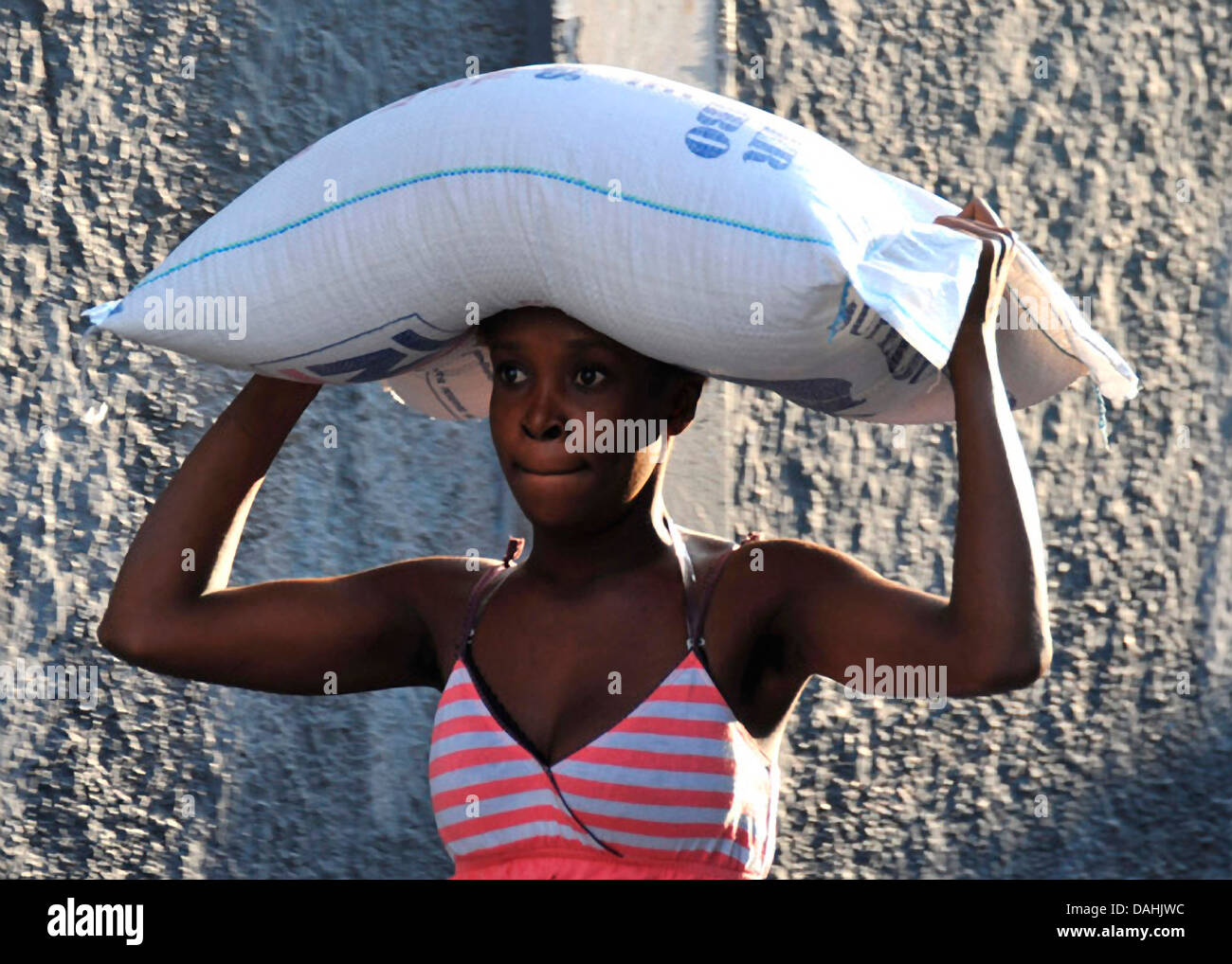 Eine haitianische Frau trägt einen 55-lbs-Beutel Reis verteilt durch die Weltgesundheitsorganisation am Standort Essen Verteilung im Anschluss an ein Erdbeben der Stärke 7,0, die 220.000 31. Januar 2010 in Port-au-Prince, Haiti Tote. Stockfoto