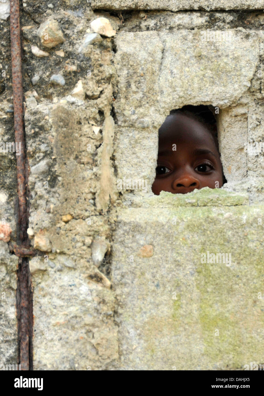 Ein wenig Menschen junge Gipfel durch ein Loch in einer Wand am Klinikum Milot, wo er wegen Verletzungen durch das Erdbeben der Stärke 7,0 behandelt wird, die 220.000 getötet 2. Februar 2010 in Cap-Haitien, Haiti. Stockfoto