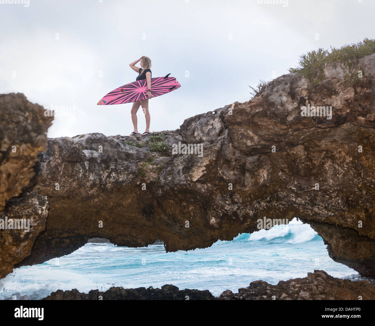 Surfer-Frau stehend auf einer Steinbrücke Surf in Cozumel, Mexiko zu betrachten. Stockfoto