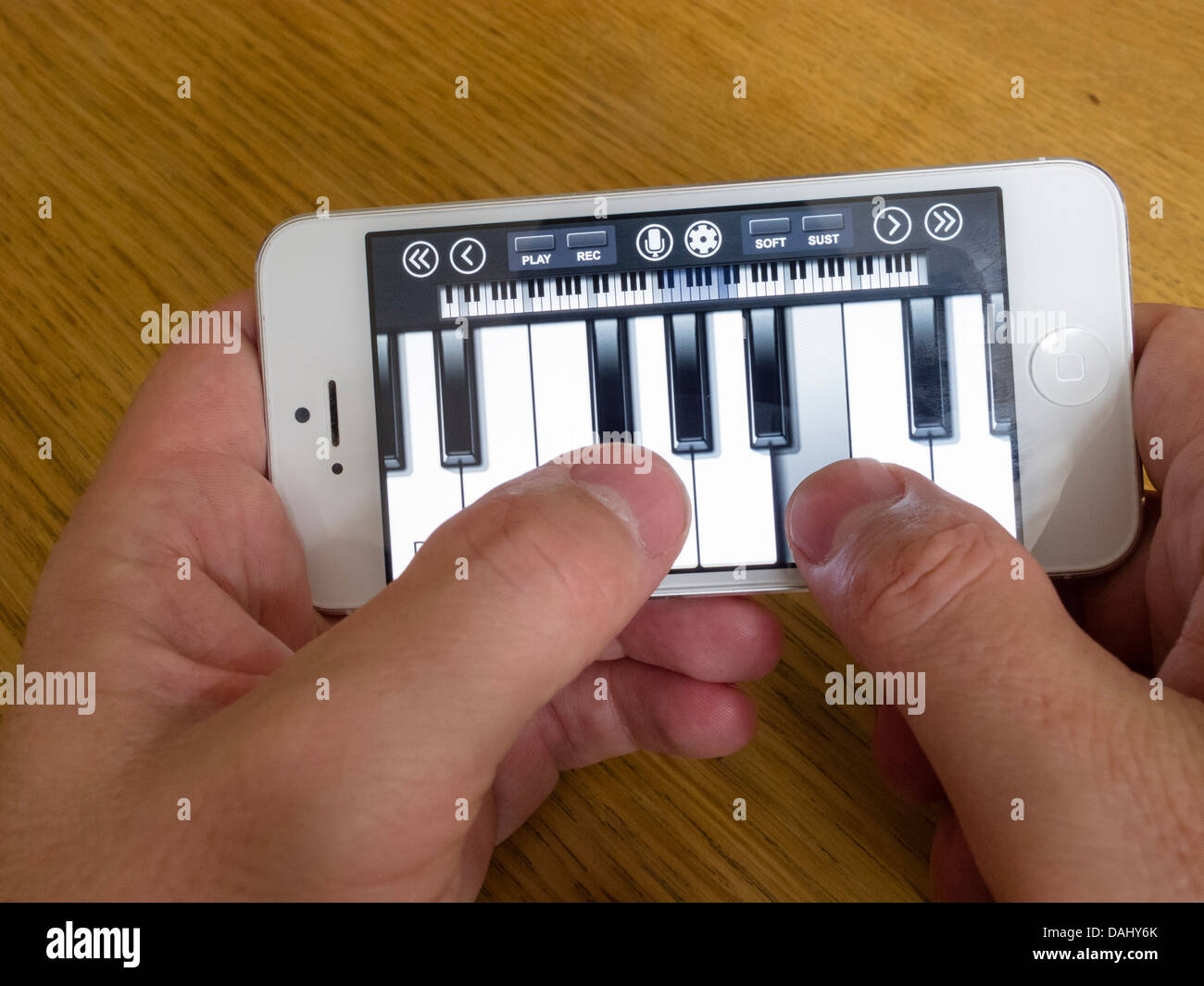 verwenden weiße iPhone 5 Smartphone zum Abspielen von Musik mit Klavier app mit Touch-ketboard Stockfoto