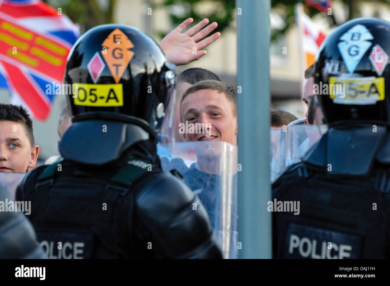 Belfast, Nordirland, 14. Juli 2013 - ein Demonstrant Loyalist winkt und lächelt von hinten Polizei-Linien. Bildnachweis: Stephen Barnes/Alamy Live-Nachrichten Stockfoto
