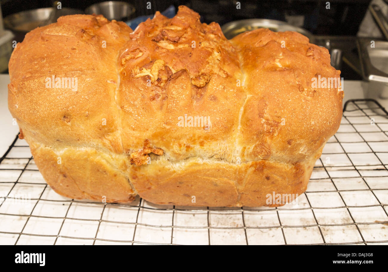 Horizontale Foto von einen großen Laib frisches Gourmet-Brot am Kühlregal mit Kochutensilien im Hintergrund Stockfoto