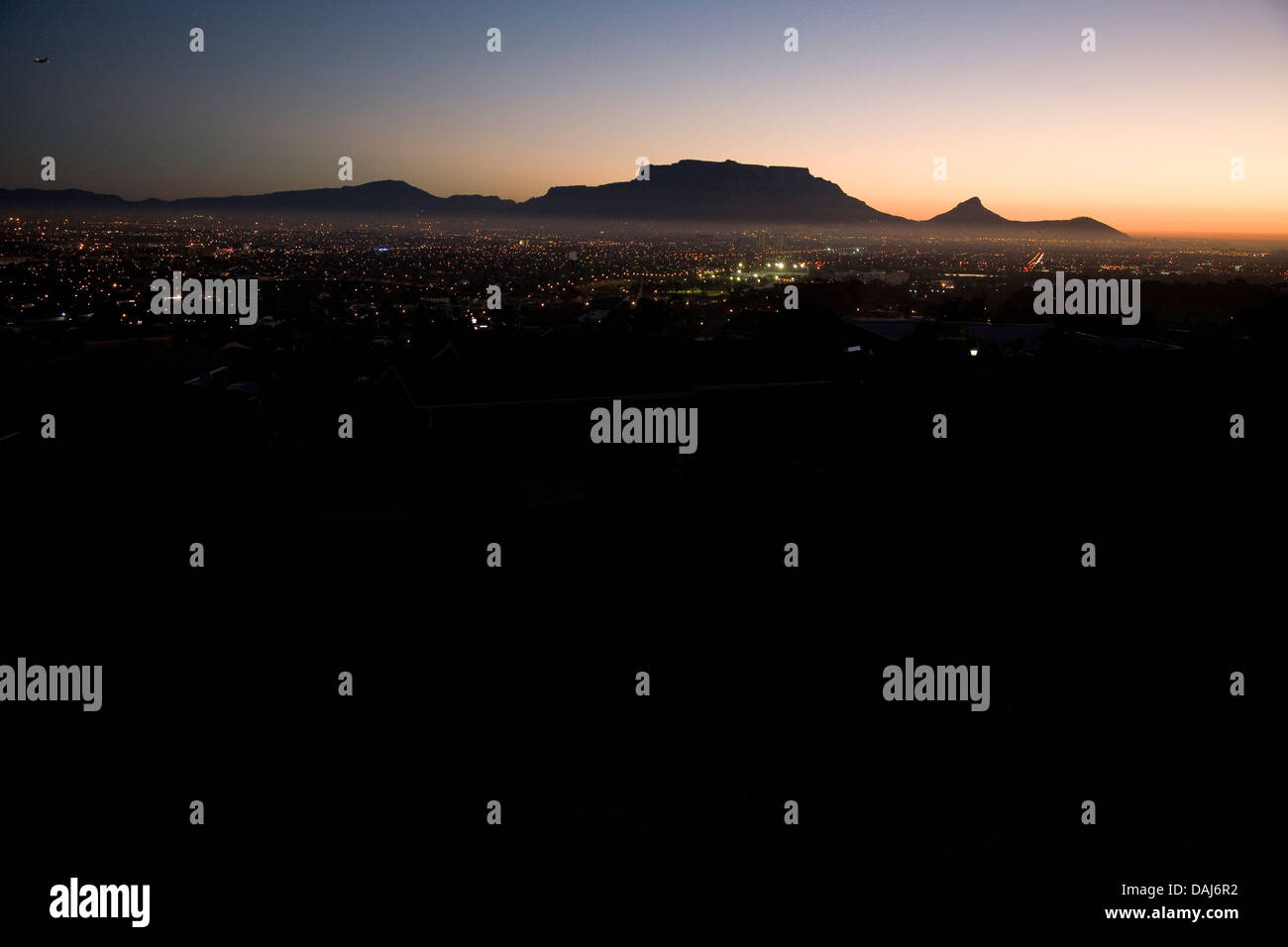 Table Mountain (links) mit Löwenkopf Silhouette (rechts) gegen die untergehende Sonne, Cape Town, Südafrika Stockfoto