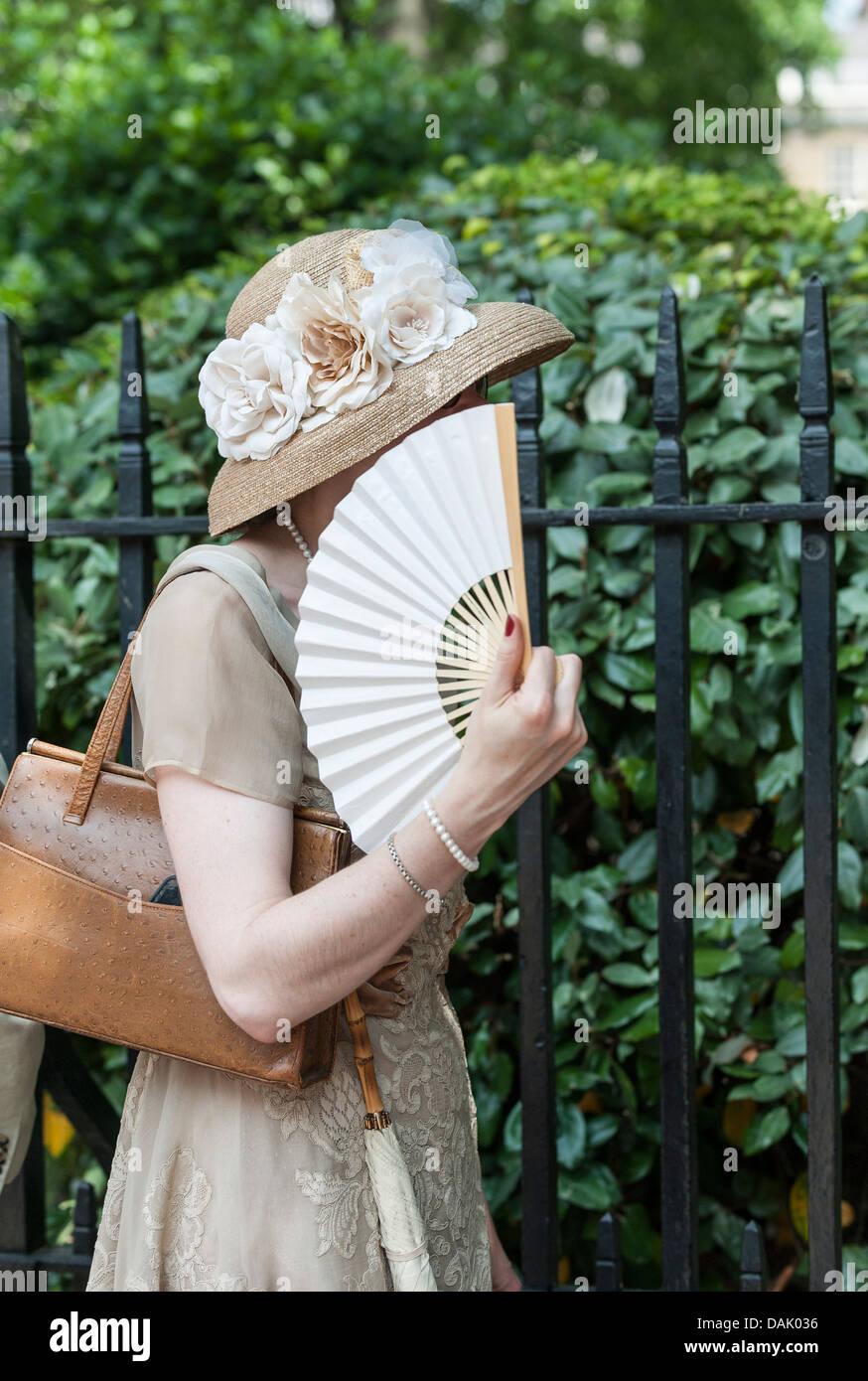 Eine Frau hält ein Fan vor ihr Gesicht als sie wartet für den Start der Chaps Olympiade in Bedford Square Gardens. Stockfoto