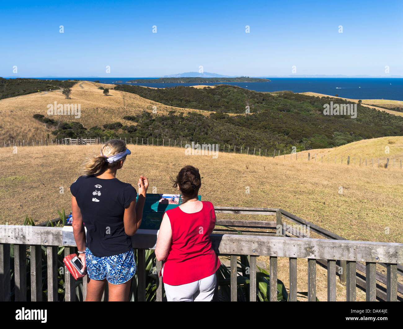 dh Shakespear Regional Park WHANGAPARAOA NEW ZEALAND Frauen lesen Storyboard Aussichtspunkt mit Blick auf die Whangaparaoa-Halbinsel Stockfoto