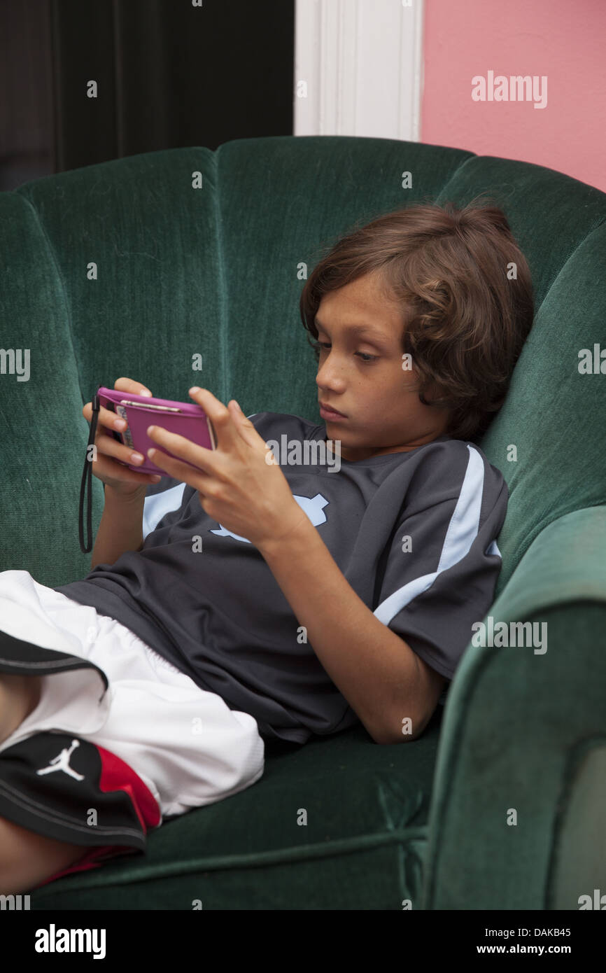 9-jähriger Junge mitten in einem Spiel auf ein Smartphone zu Hause. Stockfoto