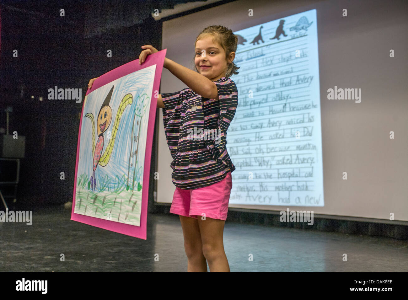 Eine Taube Mädchen nutzt Gebärdensprache zu "lesen", dass die Zusammensetzung, die sie geschrieben hat auf dem Bildschirm hinter ihr projiziert. Stockfoto