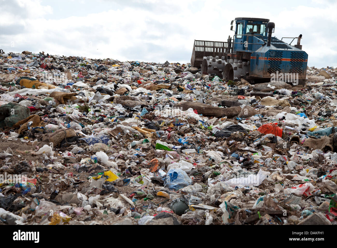 Müll türmt sich in Deponie jeden Tag während LKW mit Sand für sanitäre Zwecke abdeckt. Stockfoto