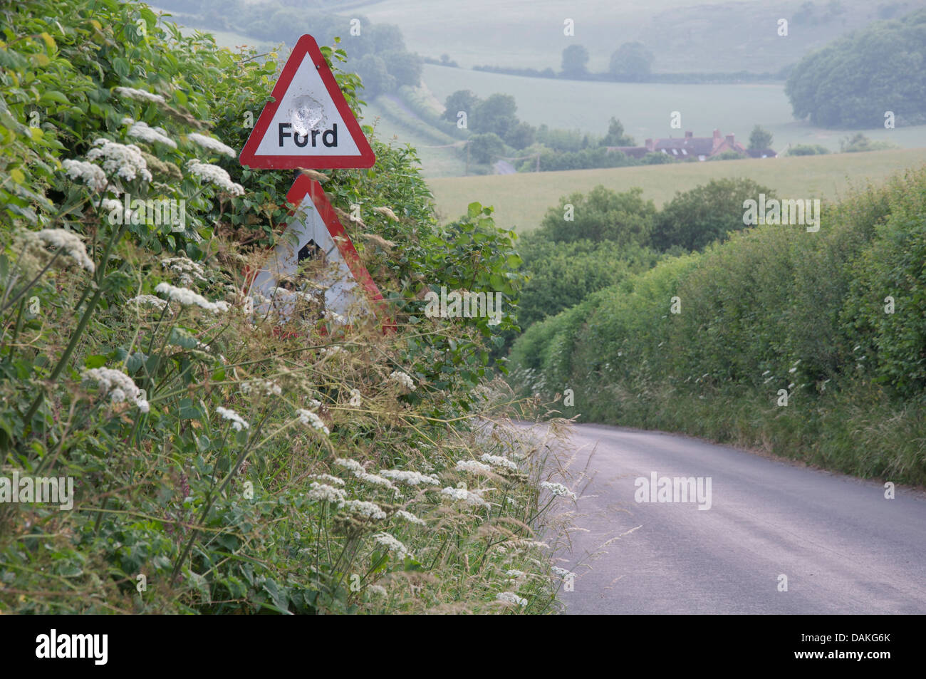 Englische Landschaft. Einen schmalen Feldweg Dorset mit hohen grünen Hecken, warnt ein Schild vor einer Furt. Jemand hat es einen Topf Schuss betrachtet. Stockfoto