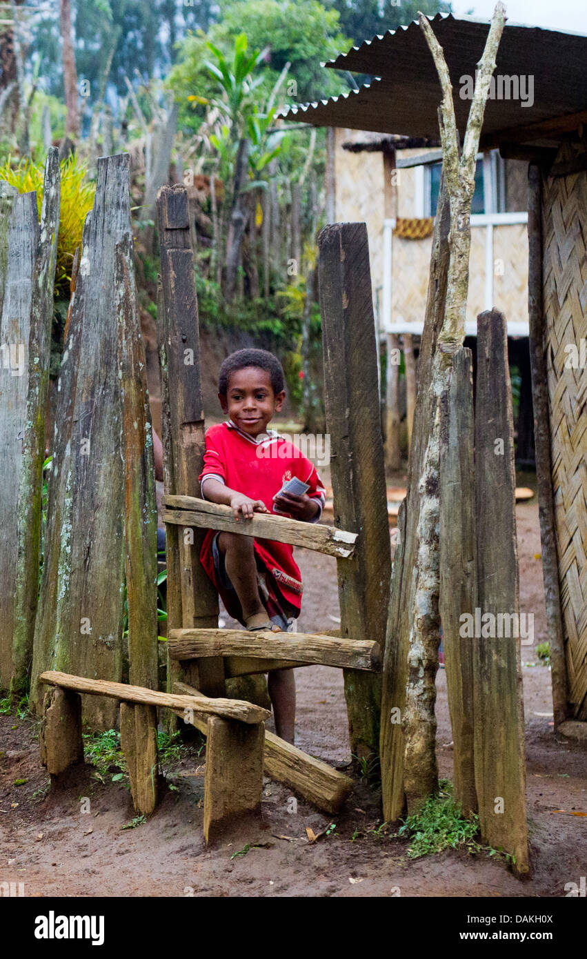 Kleiner Junge Blick durch einen Zaun vor seinem Haus, Eastern Highlands Province (Papua-Neuguinea) Stockfoto