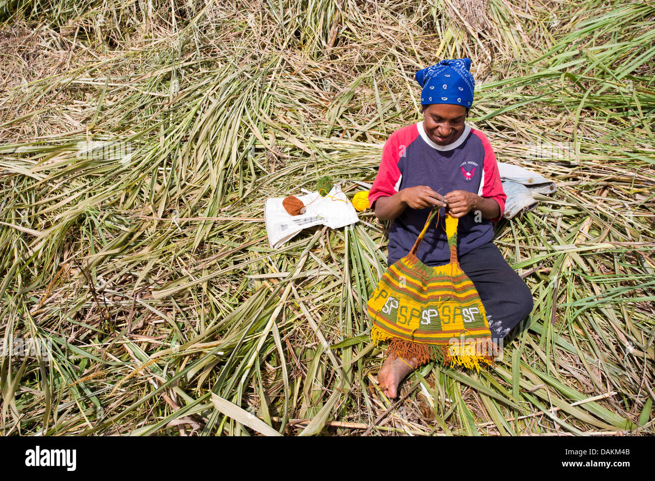 Frau sitzt im Rasen und Weben eine traditionelle Bilum Tasche im Hochland von Papua-Neu-Guinea Stockfoto