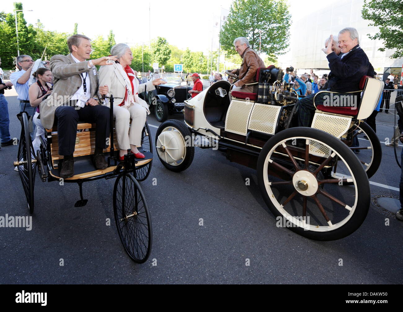 Zwei historische Vehichles Fahrt aneinander vorbei vor dem Porsche Museum zu Beginn der Auto-Parade feiert 125 Jahre Automobil in Stuttgart, Deutschland, 8. Mai 2011. Jutta Benz (2 l), Ur-Enkelin von Carl Benz, treibt ein Benz Patent-Motorwagen mit dem Mercedes-Vorsitzenden, Thomas Weber (L), auf dem Beifahrersitz. Wolfgang Porsche (R) und dem CEO-o Stockfoto