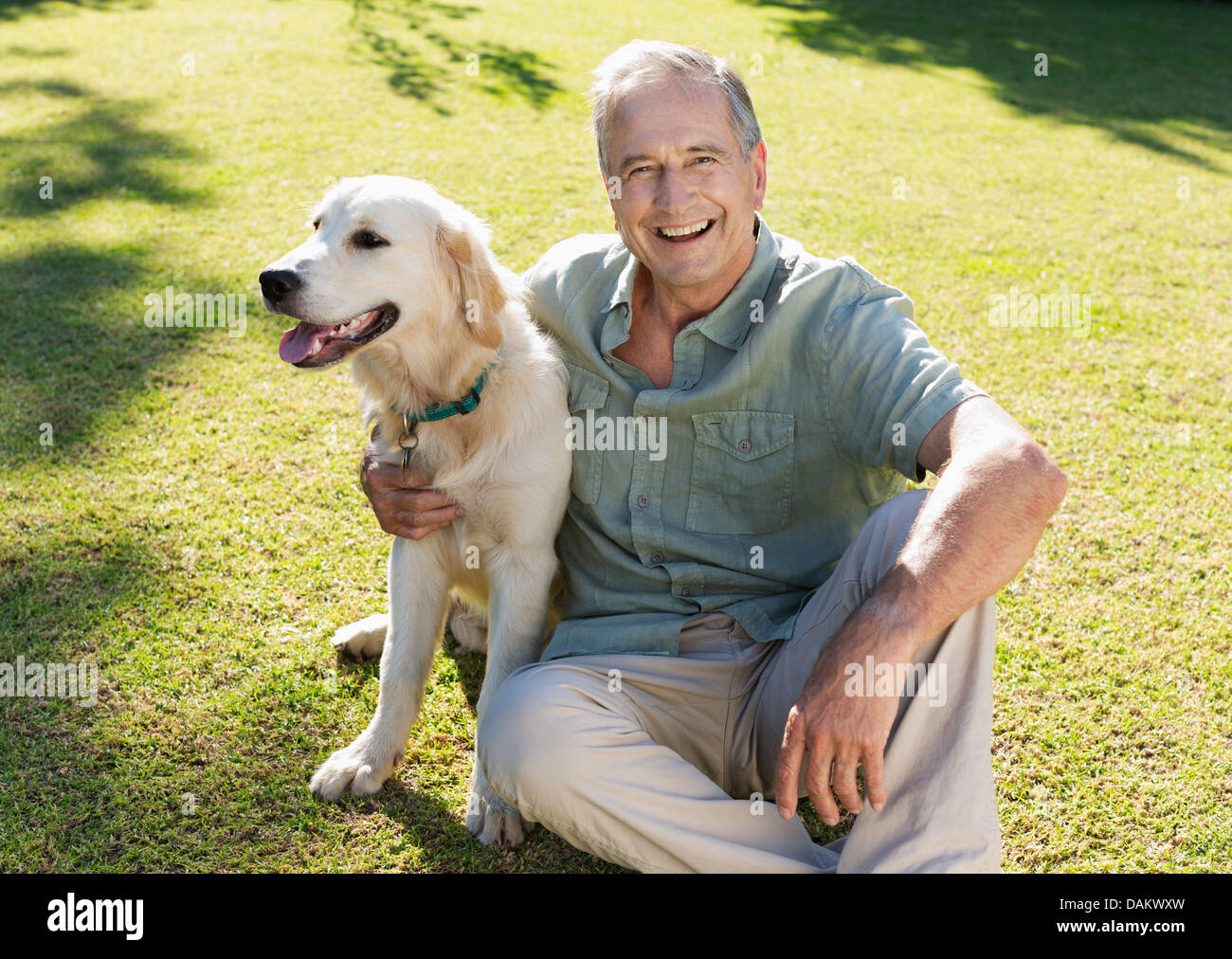 Ältere Mann umarmt Hund im Hinterhof Stockfoto
