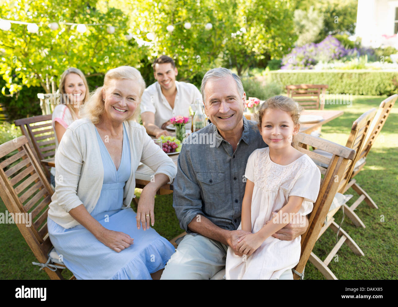Familie lächelnd am Tisch im freien Stockfoto