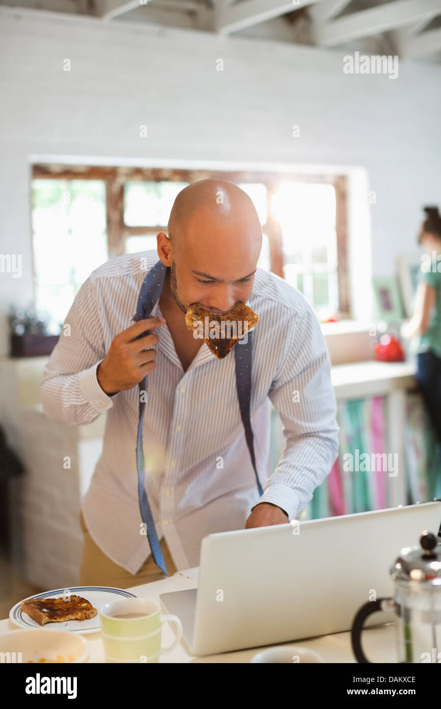 Geschäftsmann zu frühstücken und mit laptop Stockfoto