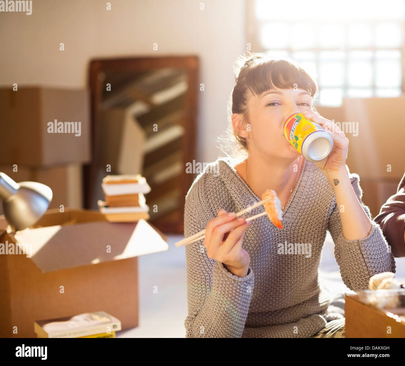 Frau trinken Soda und Sushi-Essen im neuen Zuhause Stockfoto