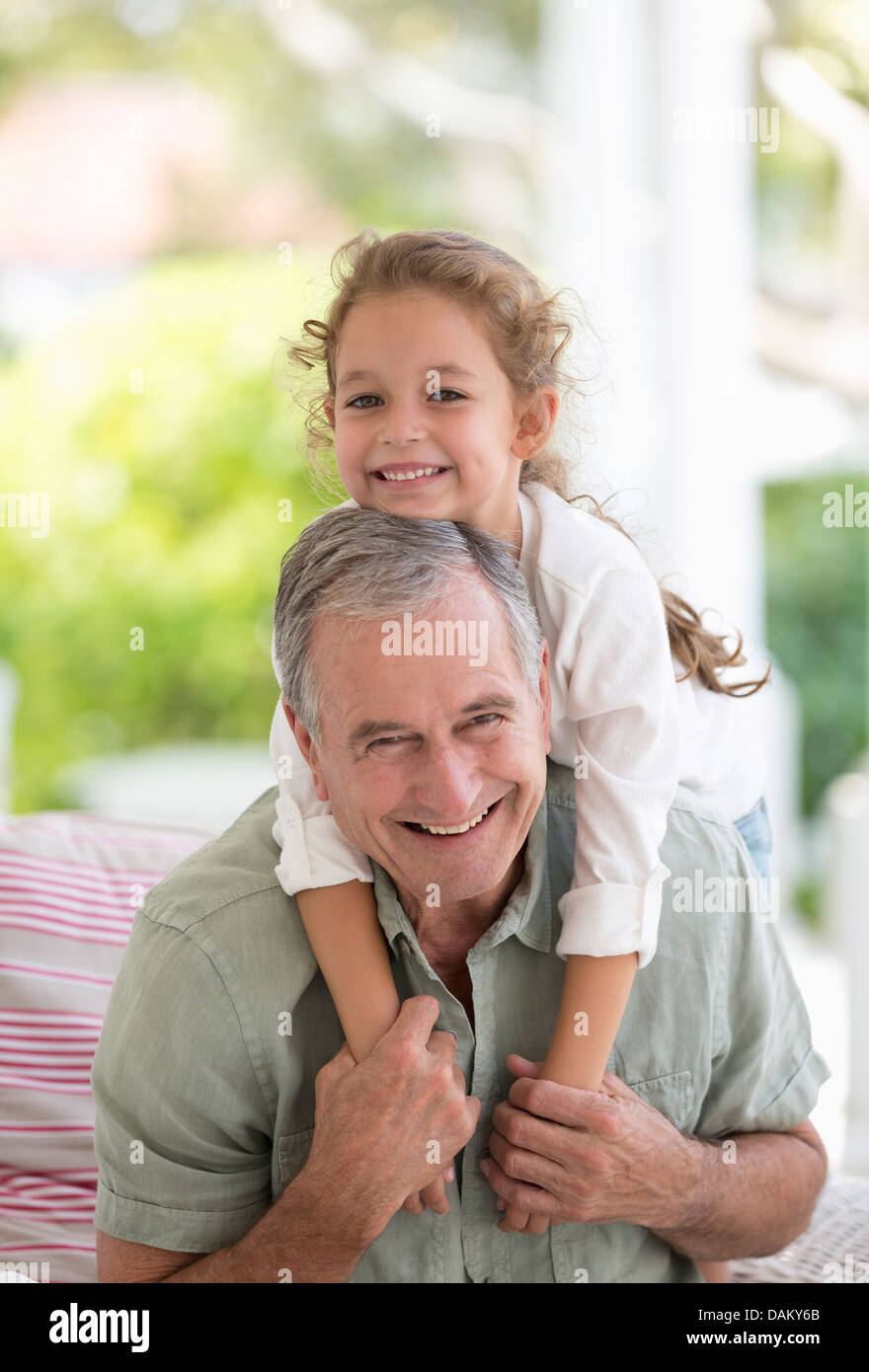 Älterer Mann mit Enkelin Huckepack Stockfoto