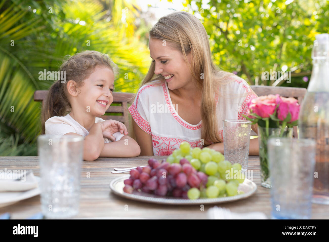 Mutter und Tochter lächelnd am Tisch im freien Stockfoto