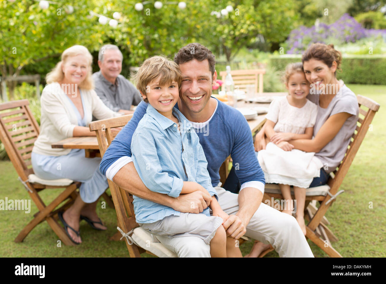 Familie lächelnd am Tisch im freien Stockfoto