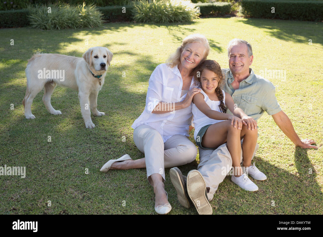 Älteres Ehepaar lächelnd mit Enkelin im Hinterhof Stockfoto
