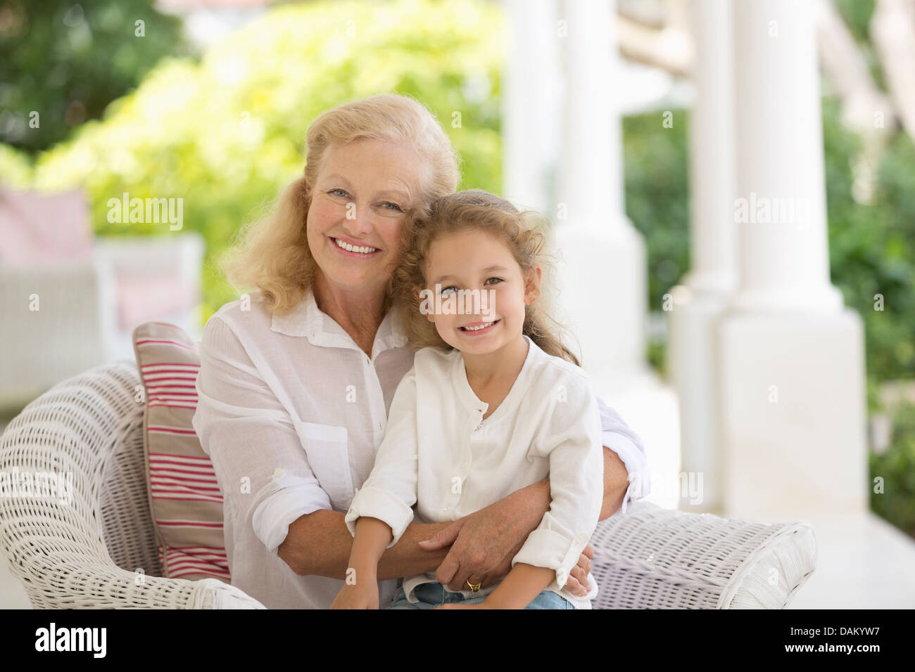 Ältere Frau und Enkelin lächelnd auf Veranda Stockfoto
