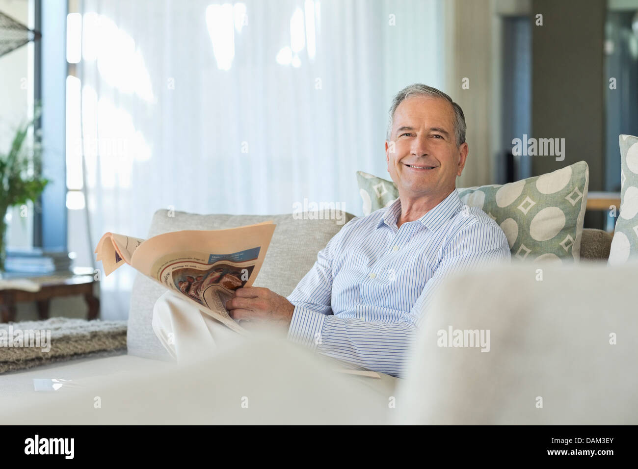 Ältere Mann liest Zeitung auf sofa Stockfoto