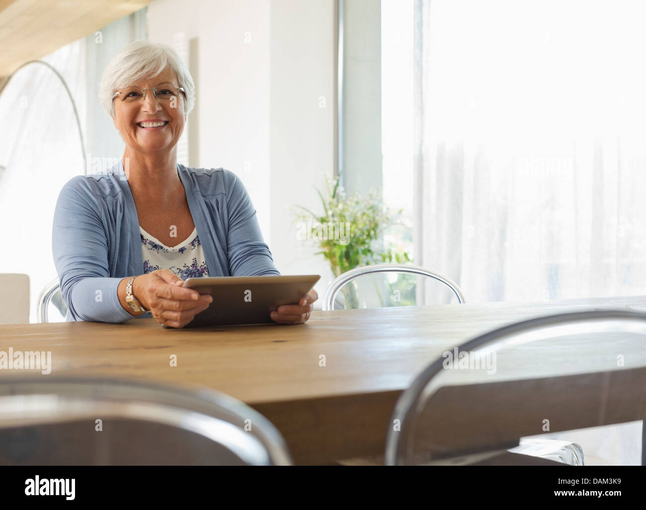 Ältere Frau mit Tablet-Computer am Tisch Stockfoto