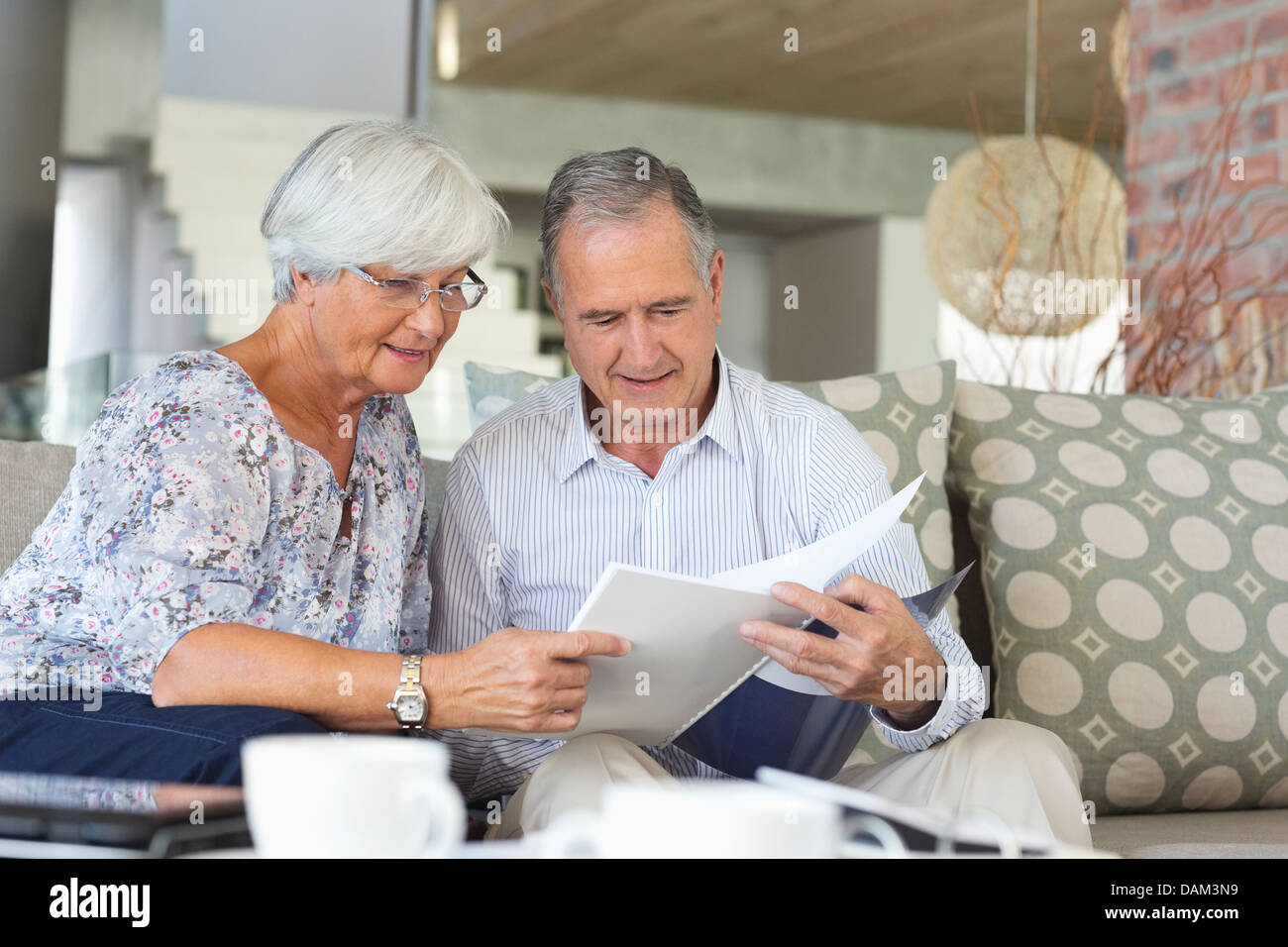 Älteres Ehepaar lesen Papiere zusammen auf sofa Stockfoto