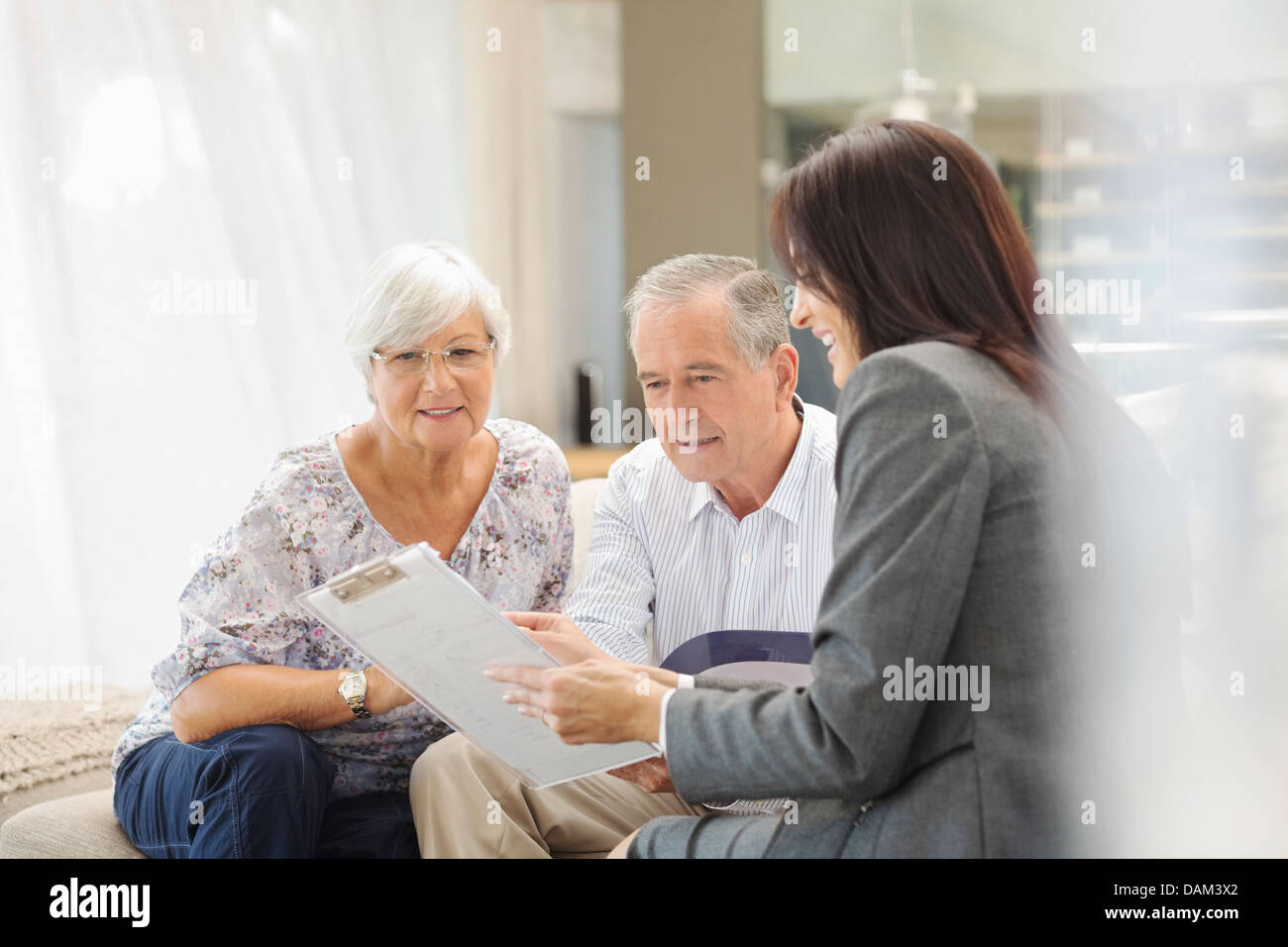 Finanzberater im Gespräch mit paar auf sofa Stockfoto