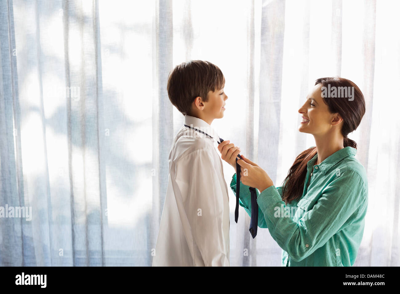 Mutter binden Sohn Krawatte am Fenster Stockfoto