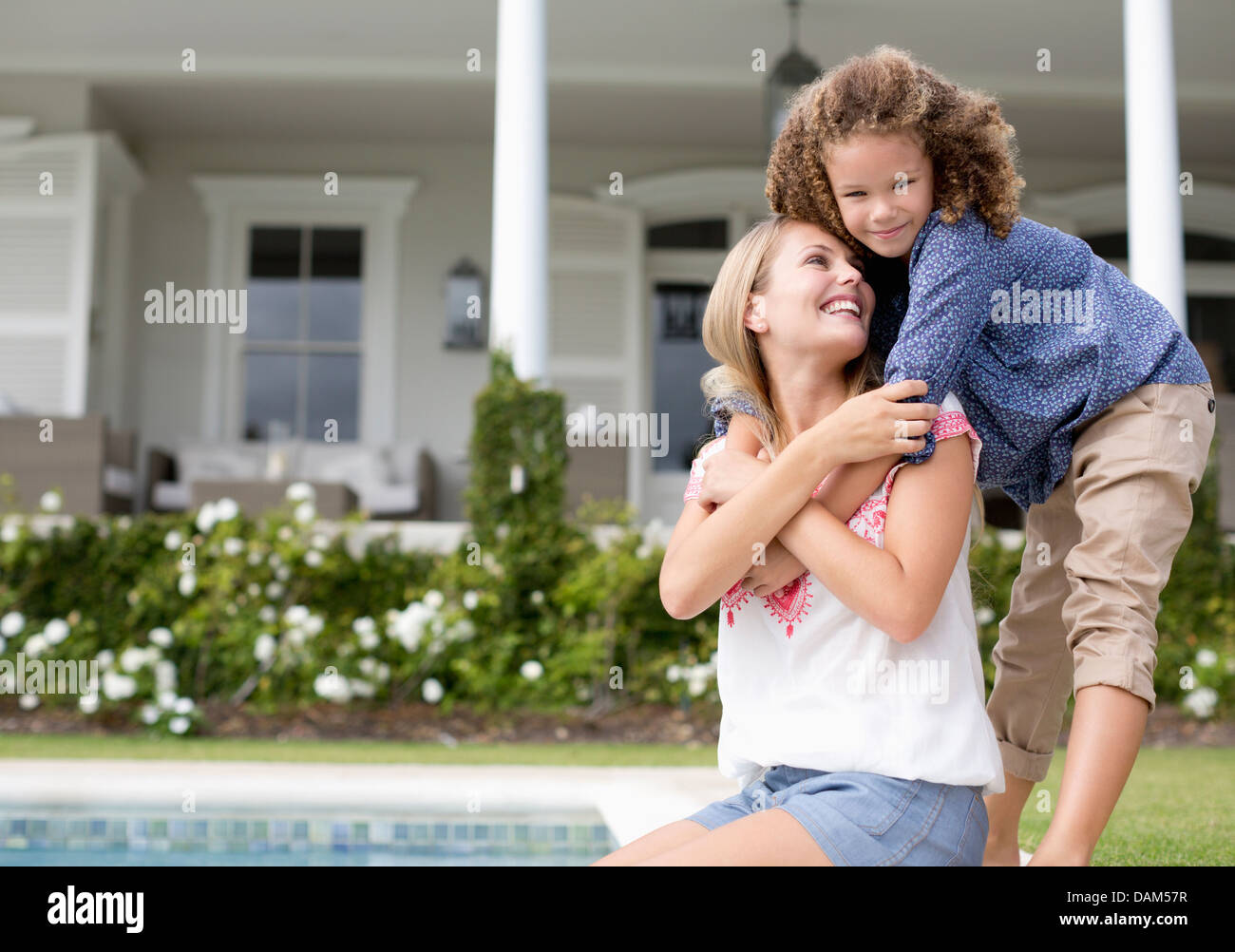 Mutter und Tochter umarmt Swimming Pool Stockfoto