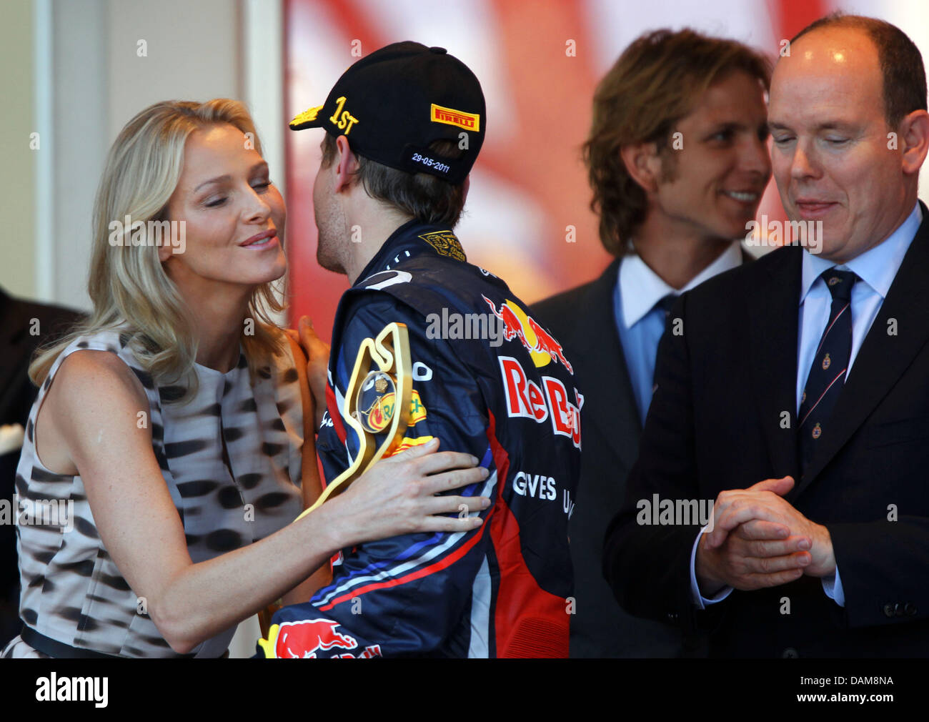 Deutsche Formel1-Fahrer Sebastian Vettel von Red Bull Racing erhält einen Kuss von Charlene Wittstock in Anwesenheit von Prinz Albert II von Monaco auf dem Podium nach dem Gewinn der Formel 1 Grand Prix von Monaco auf dem Stadtkurs von Monte Carlo, Monaco, 29. Mai 2011 lächelnd. Foto: Jens Büttner Stockfoto