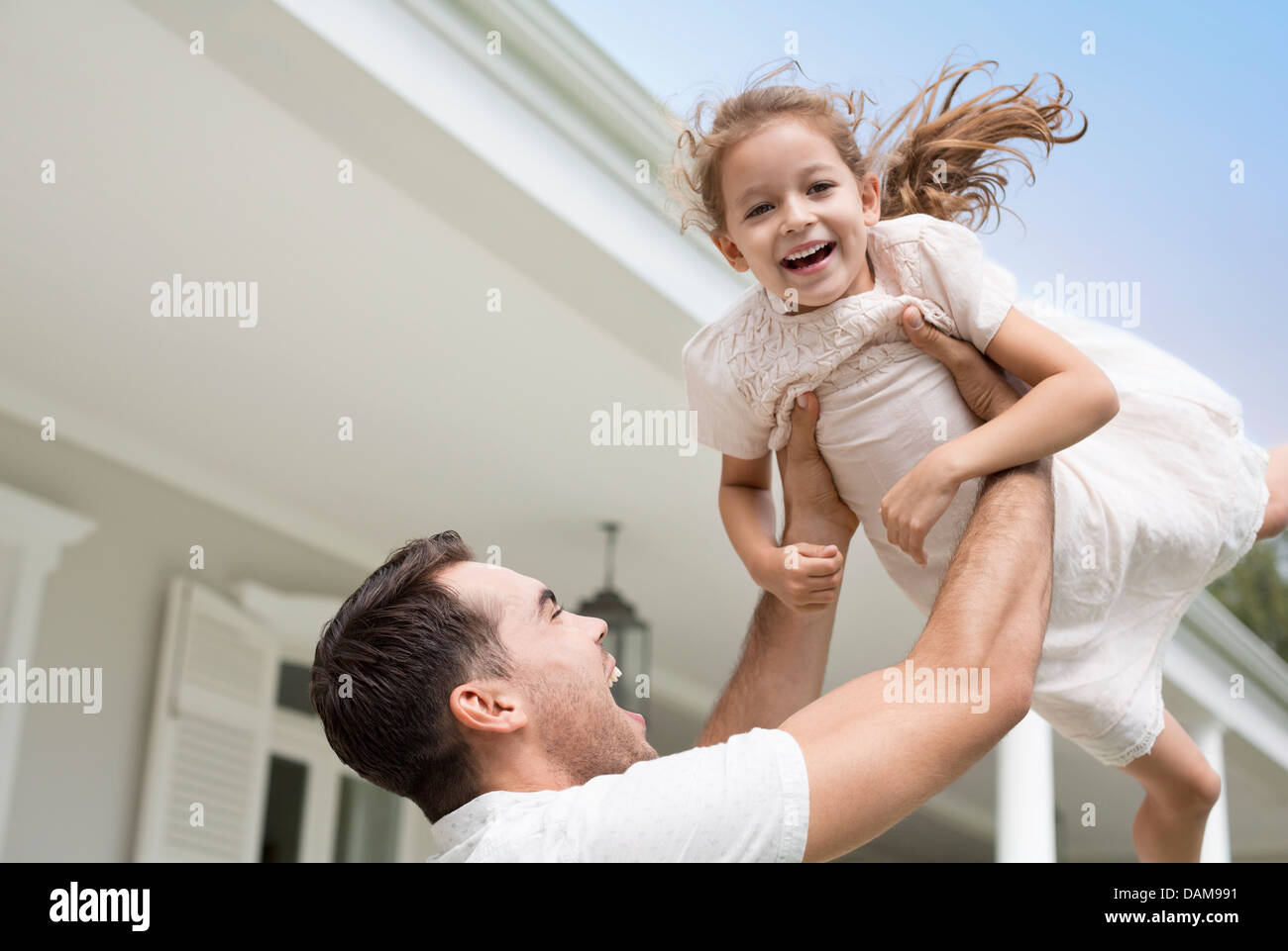 Vater und Tochter spielen vor Haus Stockfoto
