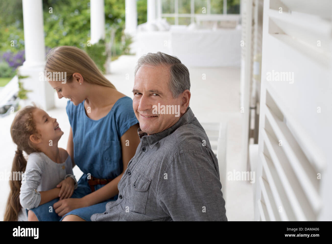 Älterer Mann lächelnd auf Veranda Stockfoto