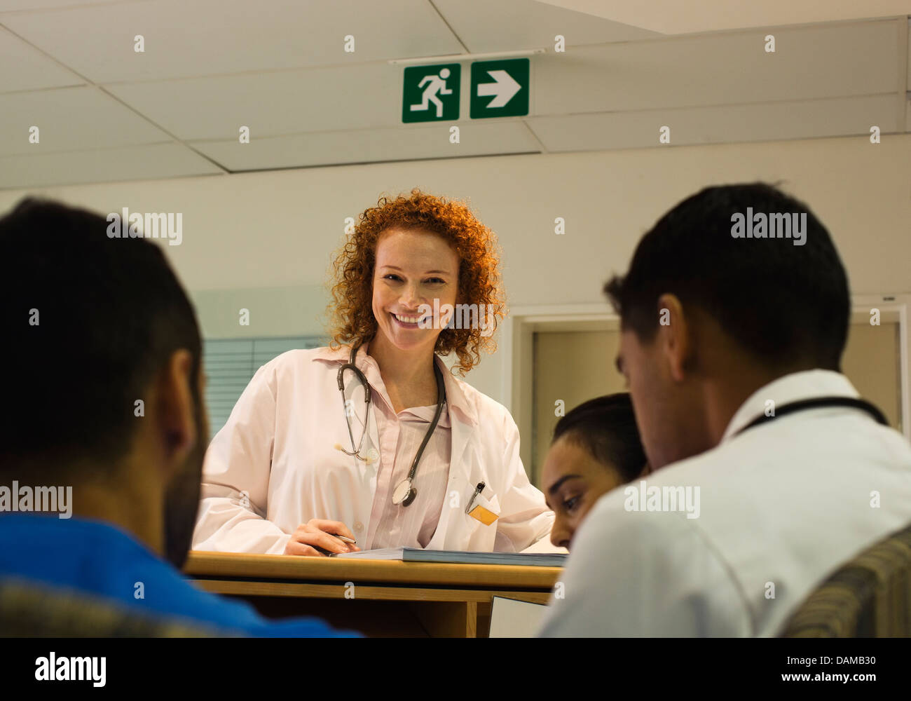 Arzt im Gespräch mit Mitarbeitern des Krankenhauses an der Rezeption Stockfoto